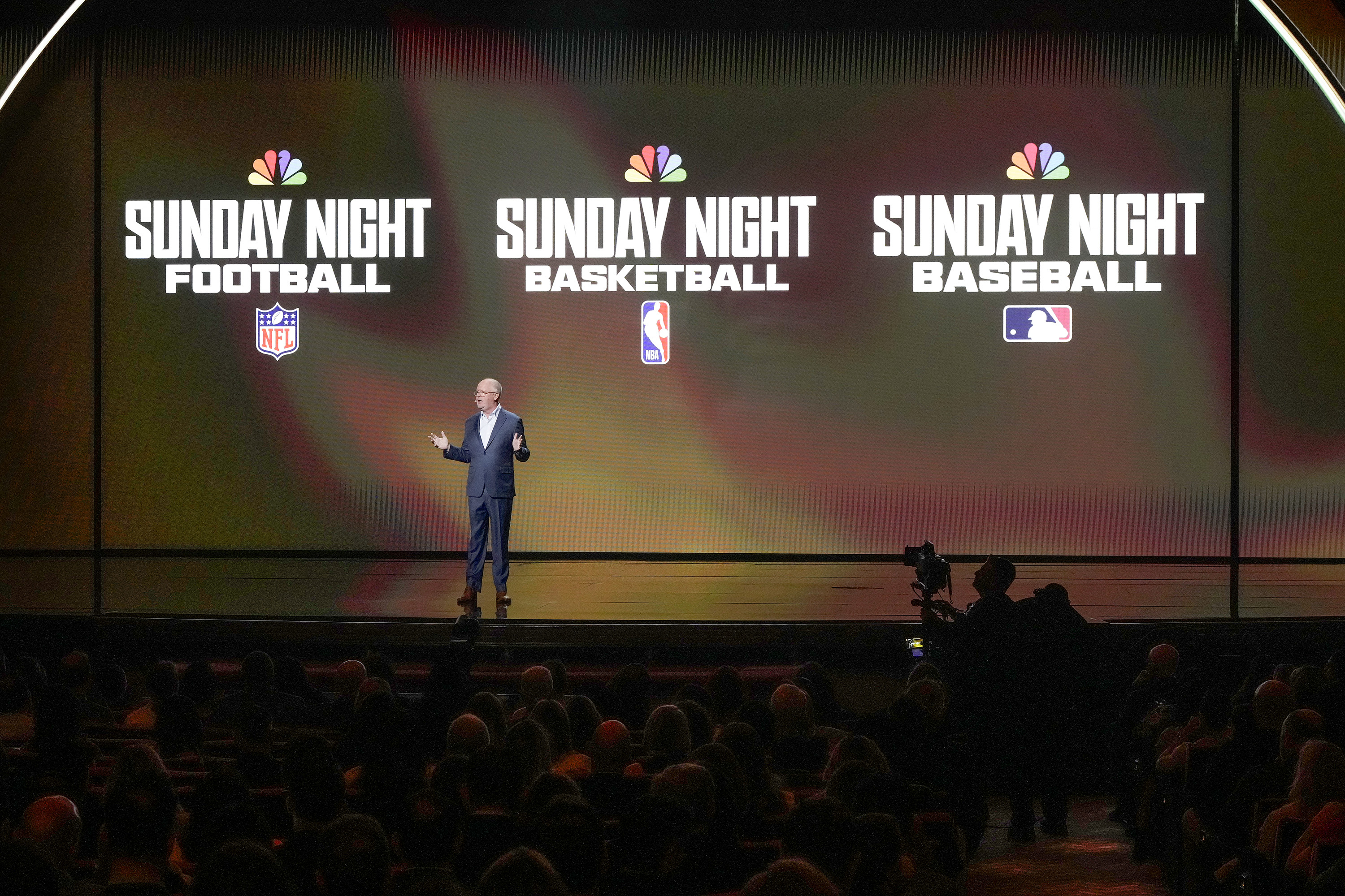 Mark Marshall stands in front of logos for Sunday Night Football, Sunday Night Basketball and Sunday Night Baseball.