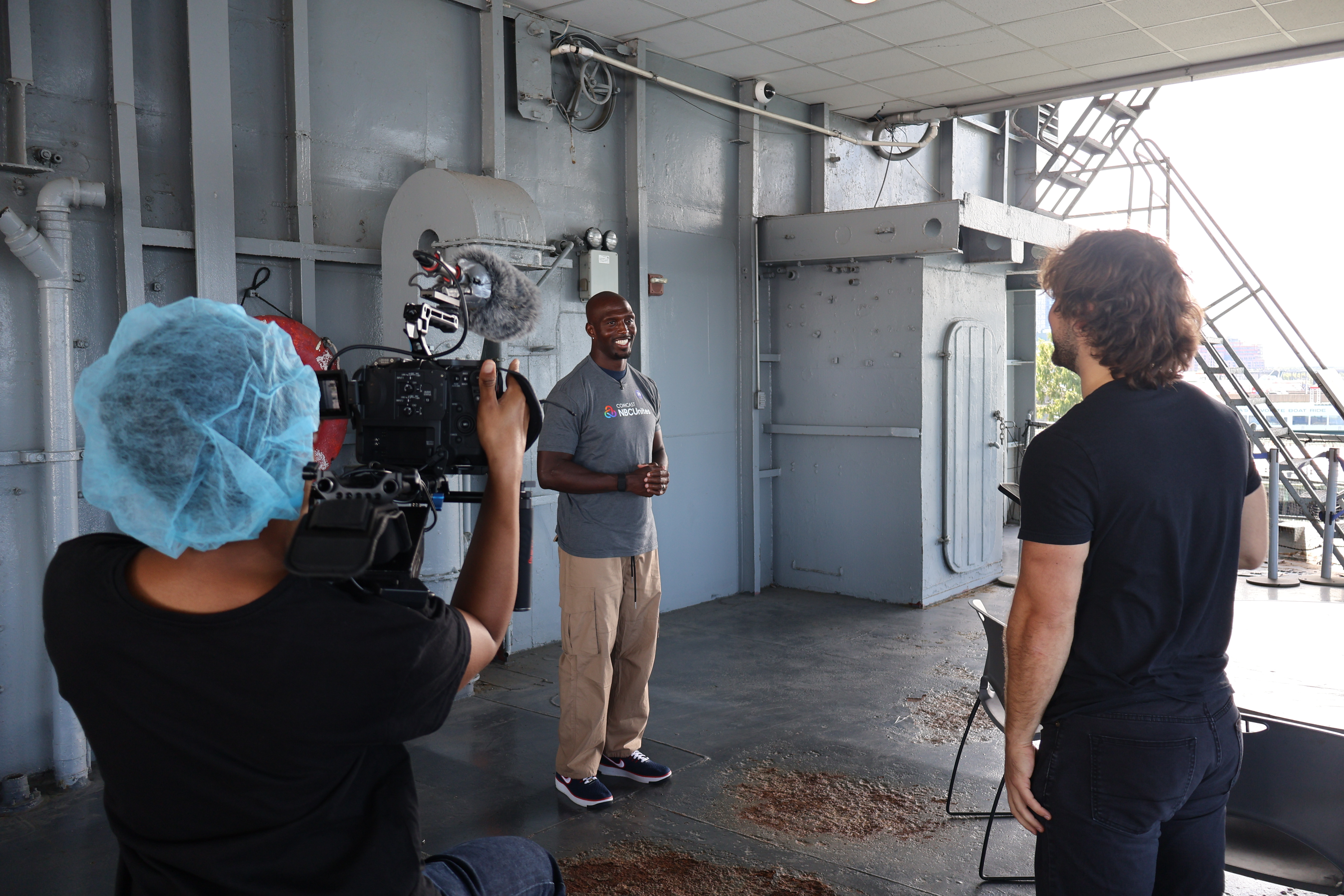 Young creators from Reel Works interviewing Devin McCourty, former NFL player and current NBC Sports studio analyst, at the meal packing event with the NFL at the Intrepid Museum